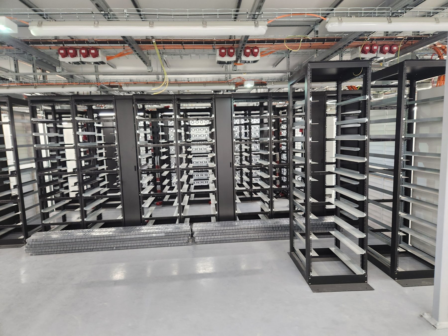 Řady technologických rozvaděčů a nosných rámů v sále datového centra